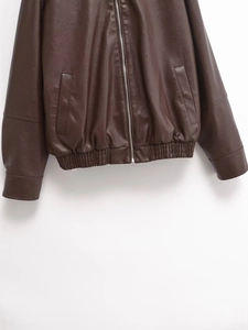 Detail of deep brown leather bomber jacket showing zipper, side pockets and elastic hem