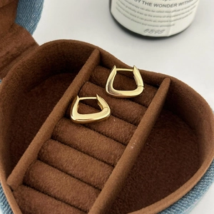 Minimalist golden geometric hoop earrings presented in a heart-shaped velvet jewelry box