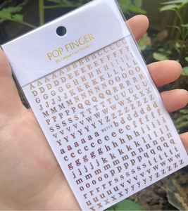 Close-up of gold 3D alphabet nail stickers in professional packaging for nail art