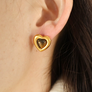 Elegant gold heart stud earrings with tiger eye stone inlay worn by a model