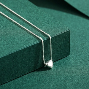 Elegant S925 sterling silver heart pendant necklace on a textured dark green display stand