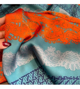 Détail d'un foulard en soie à fleurs bleu et orange montrant le lustre satiné