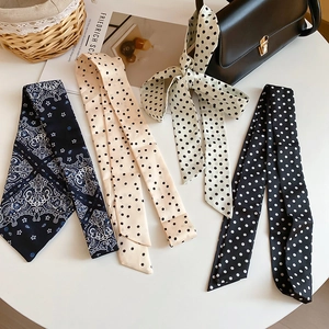 Detail of floral and polka dot silk scarves tied as decorative charms on a leather bag