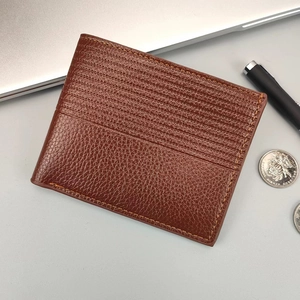 Portefeuille court pour homme en cuir grainé marron foncé sur un bureau de travail