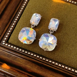 Detailed view of silver crystal earrings with colorful rhinestones on a green velvet tray