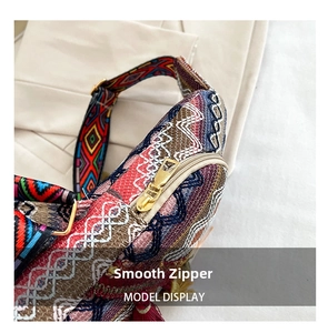 Detail of golden zipper and ethnic woven fabric texture on a stylish crossbody bag