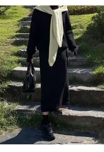 Detail of a casual black knitted sweater dress paired with a beige knit shawl scarf