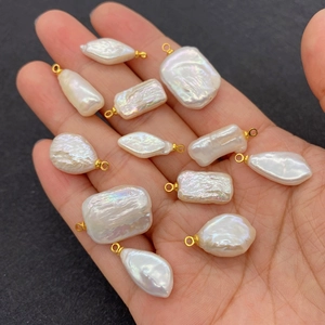 Handheld display of 12 baroque freshwater pearl pendants with golden metal loops