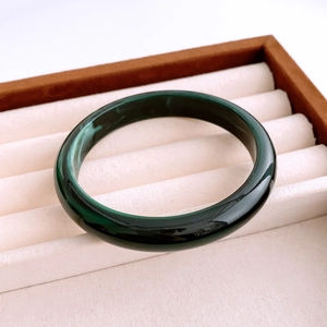 Detailed view of a dark green acrylic bangle with a marble effect in a jewelry box
