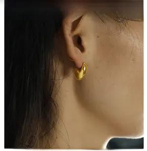 Macro close-up of high-polished 18K gold-plated titanium steel minimalist stud earrings