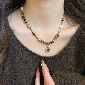 Detail of tiger eye bead necklace with teardrop pendant on a brown sweater