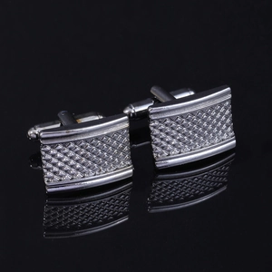 Macro view of silver cufflinks featuring detailed textured square geometric patterns