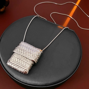 Detailed view of silver textured square pendant with snake chain on black display stand