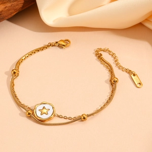 Close-up of golden double-layer stainless steel bracelet with star charm and bead detail