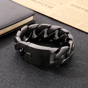 Gros plan sur un bracelet gourmette en acier inoxydable noir mat sur fond vintage