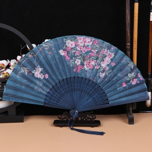 Detailed view of a dark blue folding fan with pink floral patterns and a silk tassel