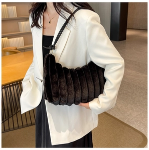 Borsa tote in peluche nera a righe verticali indossata da una modella in giacca bianca