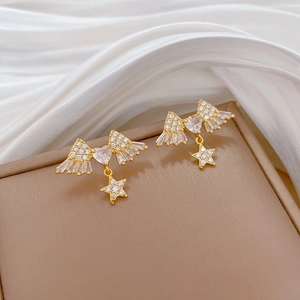 Detail of gold butterfly wing earrings with heart cubic zirconia and star pendants