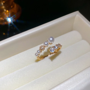 Detail of gold-plated open ring with white pearls and zircons in a jewelry gift box