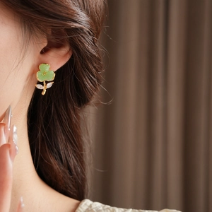 Detail view of flower stud earrings with green resin petals and white zircon accents