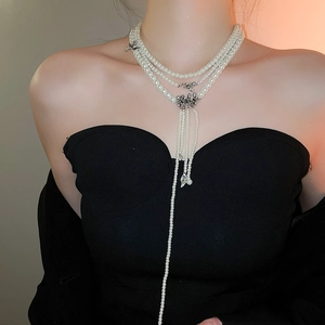 Détail d'un collier de perles multicouche avec pendentif en relief argent et glands
