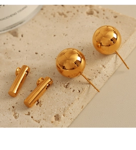 Macro shot of 18k gold plated sphere stud earrings on natural stone surface