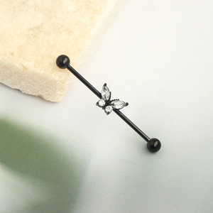 Black industrial barbell piercing with a butterfly zircon design and steel balls