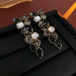 Détail de boucles d'oreilles vintage avec cristaux noirs et gris fumé sur monture dorée