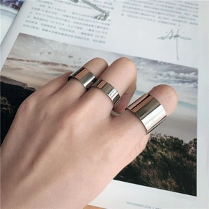 Close-up of three different widths of polished stainless steel rings on a hand