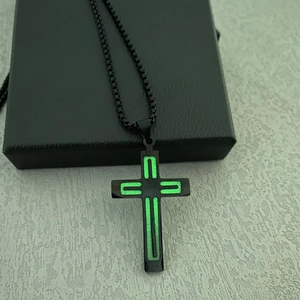 Detailed macro view of black stainless steel cross necklace with glowing green stripe detail