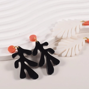 Abstract coral leaf resin earrings with golden links on a white wavy background