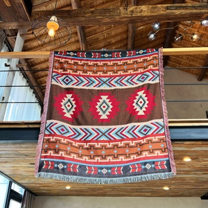 Detail showing the thick woven texture and fringed edges of a bohemian style camp blanket