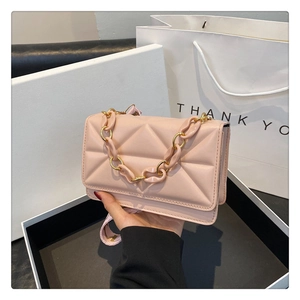 Detail of pink quilted crossbody bag featuring a thick chain strap and metal hardware