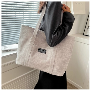 Close-up of light gray canvas tote bag with textured fabric on a fashion model