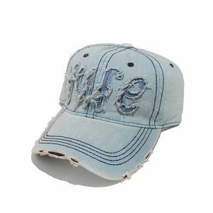 Detailed view of frayed edges and 'Wife' embroidery on a vintage washed denim baseball cap