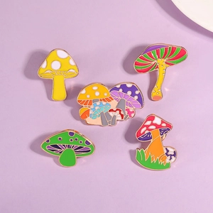Set of five colorful mushroom enamel pins displayed on a soft lavender background