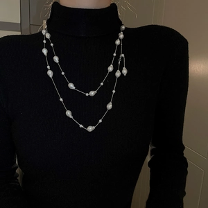 Close-up of double-layered long necklace with baroque pearls on a black sweater