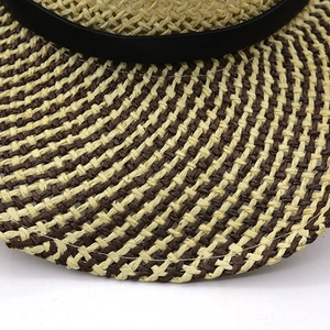 Close-up of beige and brown woven raffia texture and fine stitching on brim