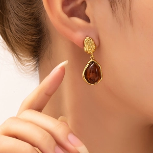 Close-up of French style gold irregular lava texture studs with amber teardrop charms