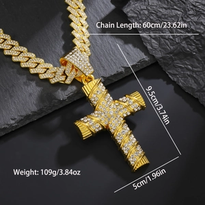 Close-up of gold iced out cross pendant with cubic zirconia on black stone surface