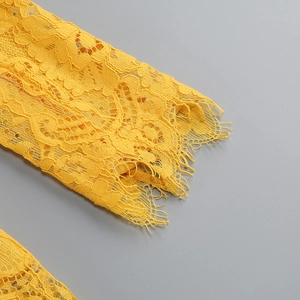 Dettaglio macro del pizzo giallo brillante con bordi a ciglia e motivi floreali