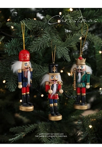 Drei bemalte Nussknacker-Holzanhänger hängen an einem beleuchteten Weihnachtsbaum