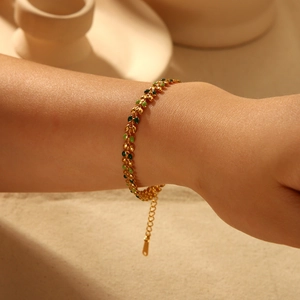 Gold-plated stainless steel bracelet featuring green olive leaf charms worn on a wrist
