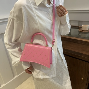 Pink quilted handbag with gold heart studs and shoulder strap shown in a cafe setting