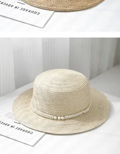 Detail of elegant beige boater hat featuring dual-row pearl embellishment and woven texture