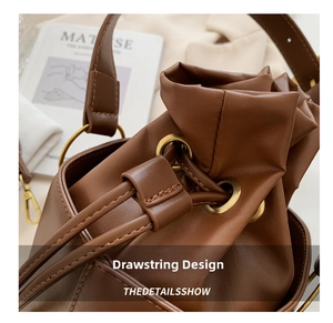Detail of vintage brown leather bucket bag showing the drawstring closure and metal eyelets