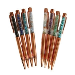 Eight rose gold metal ballpoint pens filled with colorful crystal stones on white background