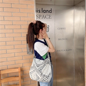 Street style view of a large paisley print canvas tote bag worn by a model at a cafe