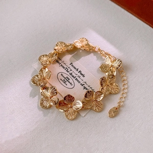 Detail of elegant gold flower link bracelet on vintage card and white fabric background