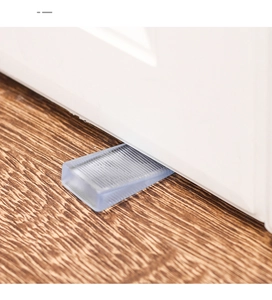 Close-up of transparent wedge furniture shims leveling a white door on wooden floor